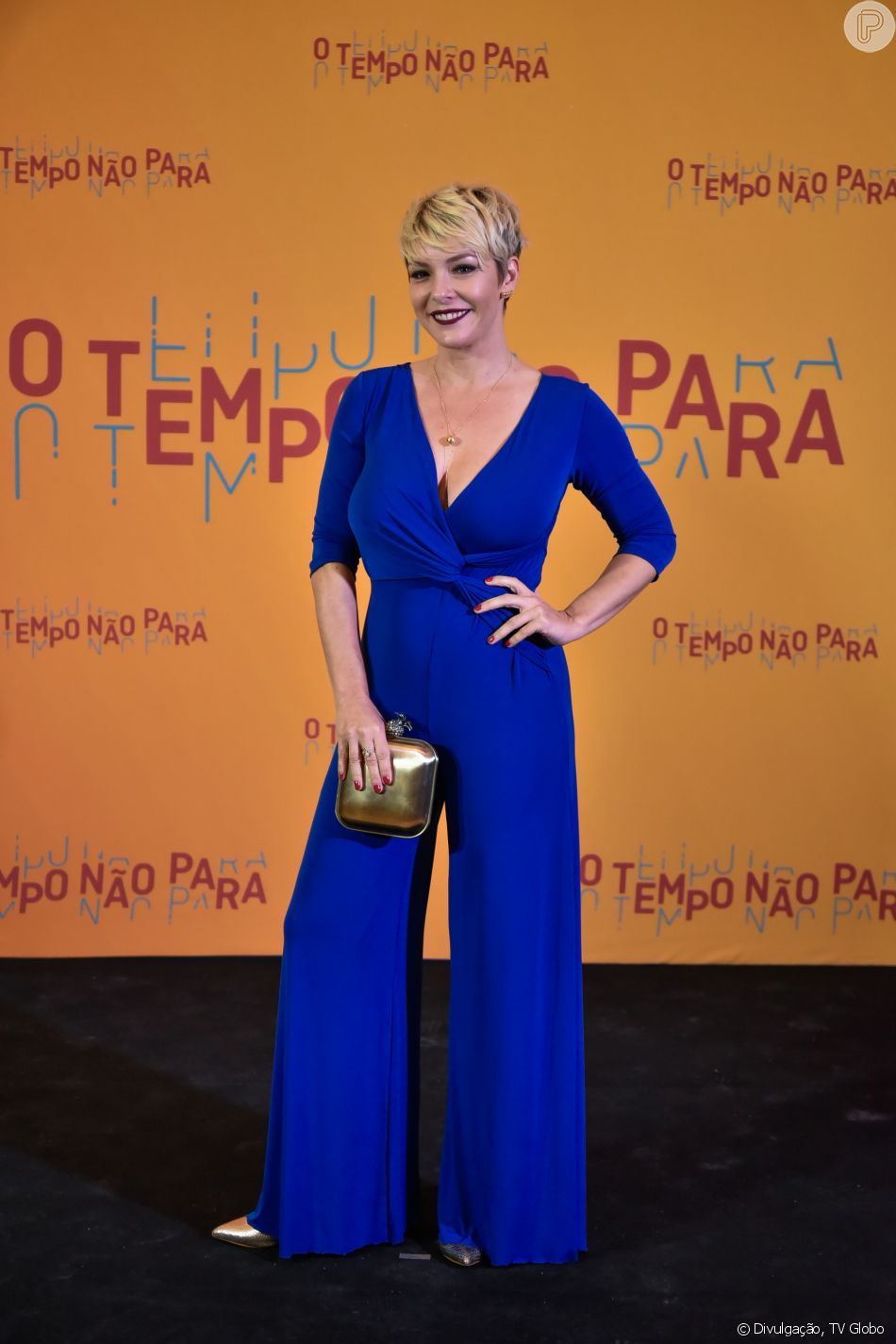 Regiane Alves apostou num macacÃ£o azul royal Alphorria e acessÃ³rios dourados na festa de lanÃ§amento da novela 'O Tempo NÃ£o Para', em 16 de julho de 2018