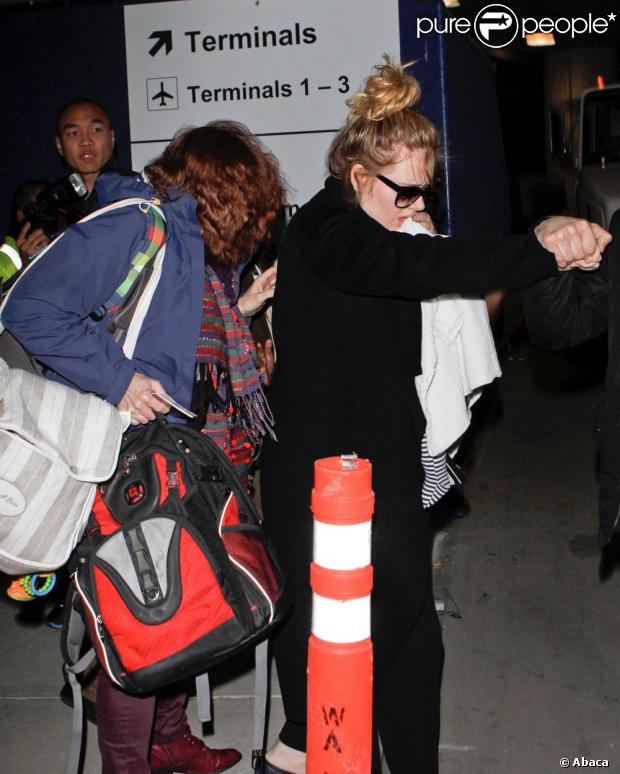 Adele esconde rosto do filho durante desembarque no aeroporto de Los Angeles, nos Estados Unidos, onde chegou para a festa da premiação do Globo de Ouro, em 11 de janeiro de 2013