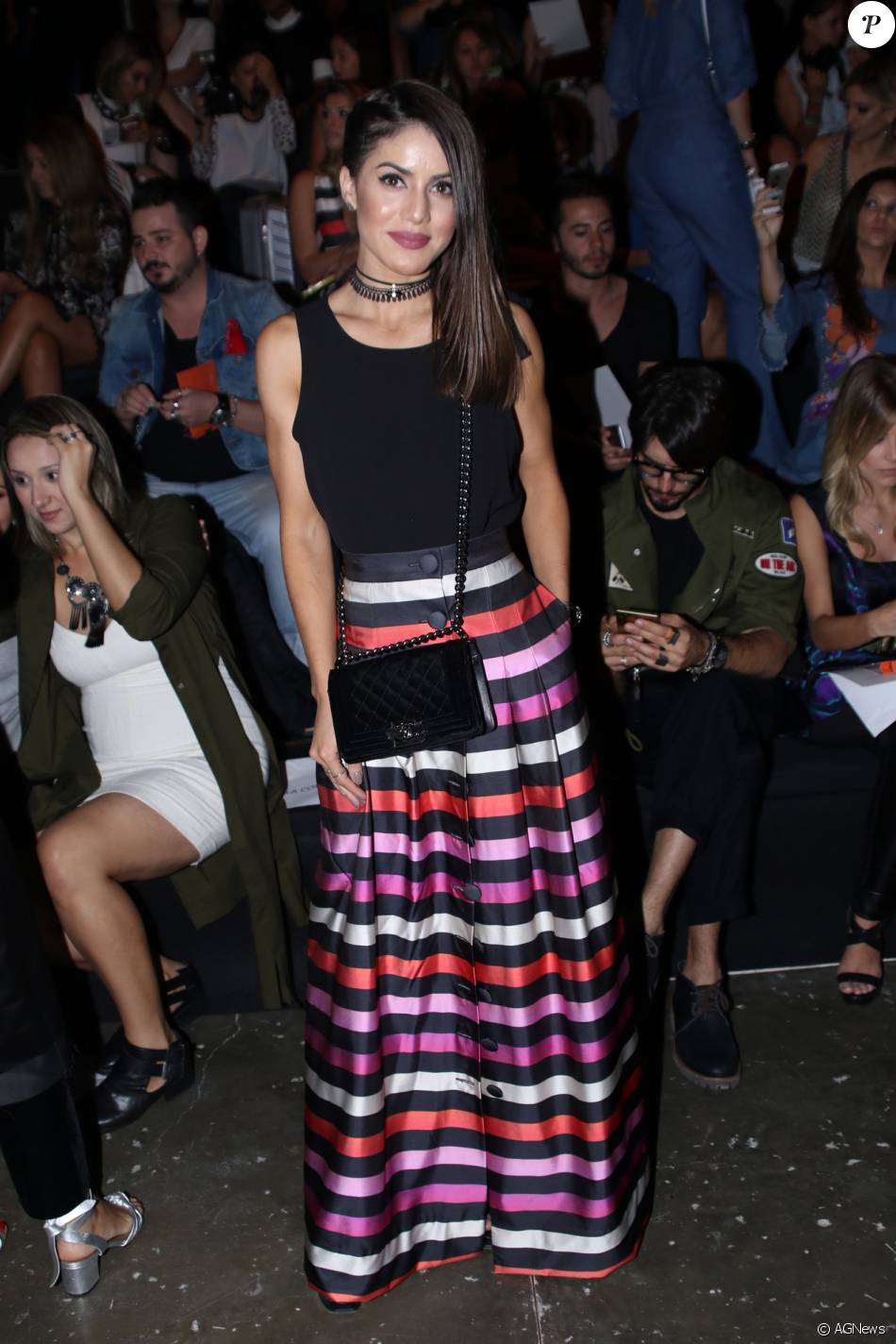 A blogueira de moda Camila Coelho usou saia listrada da grife Apartamento 03 para assistir ao desfile da marca na terça-feira, 26 de abril de 2016. Para compor o look, bolsa Chanel e sandálias de salto YSL
