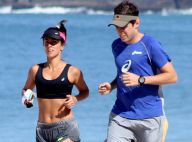 Carol Barcellos mostra barriga sequinha durante corrida na praia com o marido