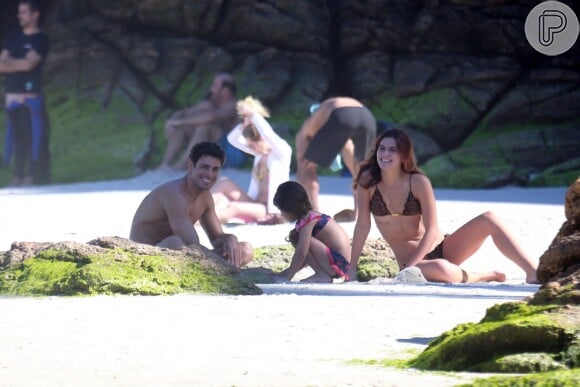 Cauã Reymond e a namorada, Mariana Goldfarb, levam filha do ator à praia