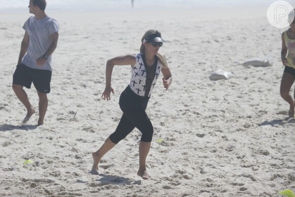 Flávia Alessandra corre na areia da praia. De acordo com o profissional, o objetivo da atriz é secar