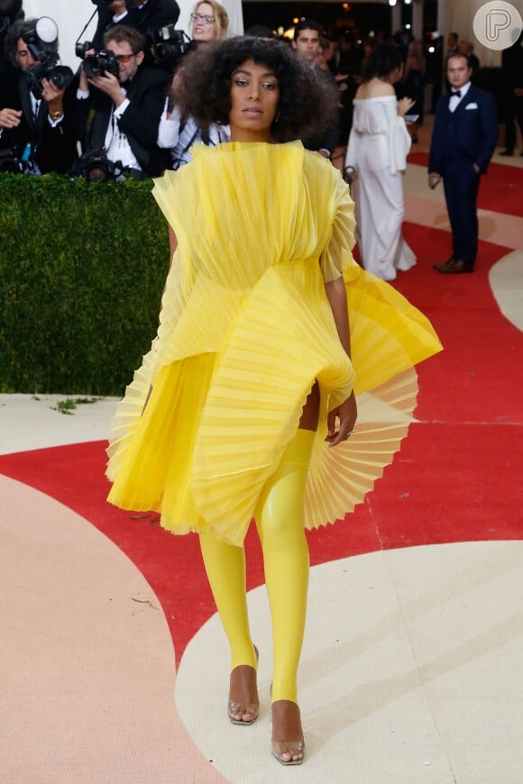 Solange Knowles supreendeu no Met Gala 2016 ao usar vestido amarelo cheio de dobraduras com meias até a coxa e sandálias transparentes