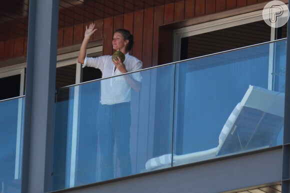 Gisele Bündchen aproveitou para tomar água de coco e acenou para os fãs que a viram no terraço