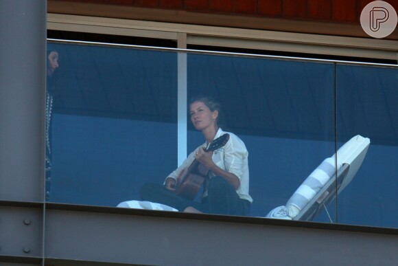 Gisele Bündchen apareceu na sacada do hotel em que está hospedada e arriscou tocar violão