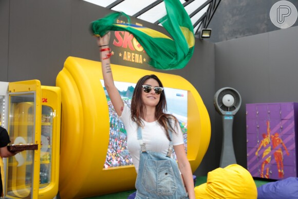 Thaila Ayla segura a bandeira do Brasil no jogo de futebol da seleção feminina