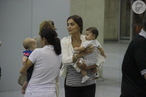 Juliana Paes carrega o filho caçula no colo no aeroporto do Rio de Janeiro