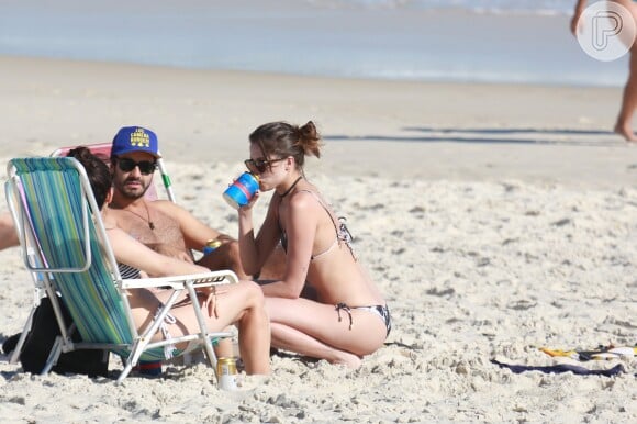 Agatha Moreira bebe uma latinha durante conversa com os amigos na praia