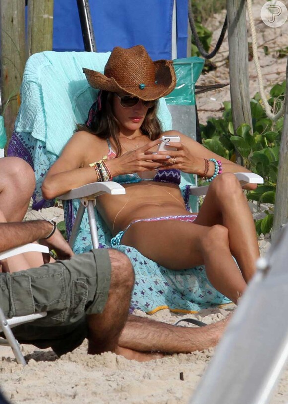 Top mexe no celular sentada na cadeira da praia