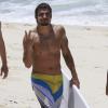 Caio Castro exibe os músculos e acena para o fotógrafo após ser flagrad o surfando no Rio