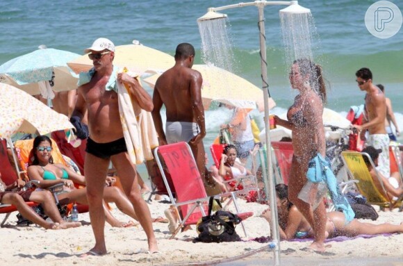 Oscar caminha com uma das amigas na praia carioca