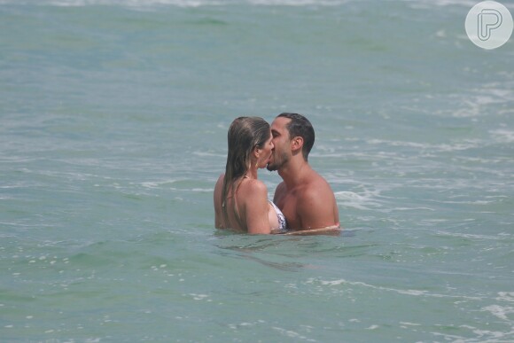 Após o treino, Julio Rocha e Patricia Gutkoski correram para o mar. Apaixonados, eles trocaram beijos quentes nas águas da Barra da Tijuca