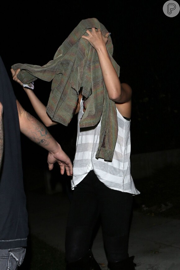 Selena Gomez usa o casaco para se esconder dos fotógrafos