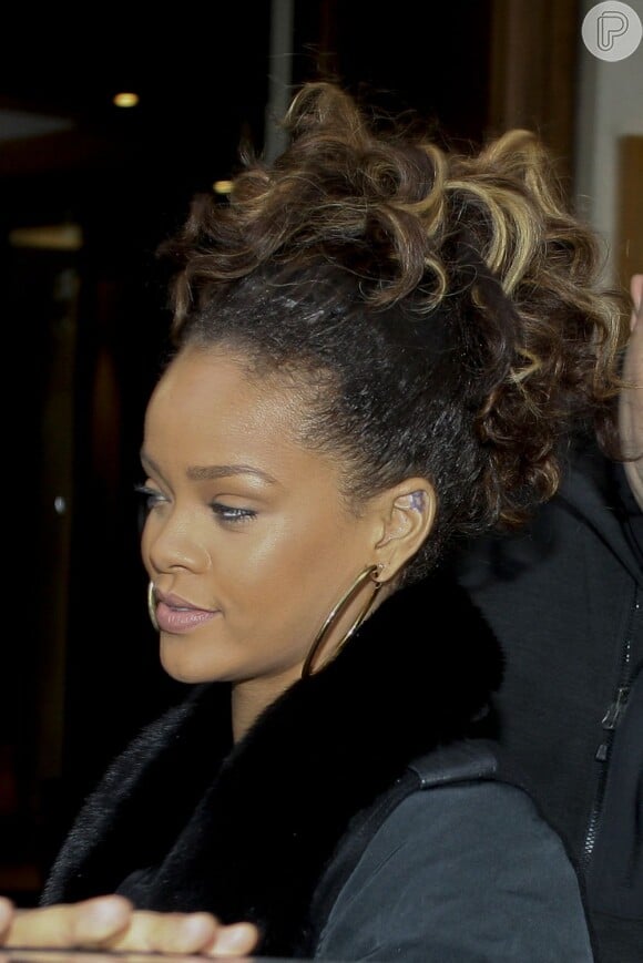 Rihanna deixa seu hotel em Paris, na França, com os cabelos cacheados e volumosos, em um penteado com mechas loiras, em outubro de 2011