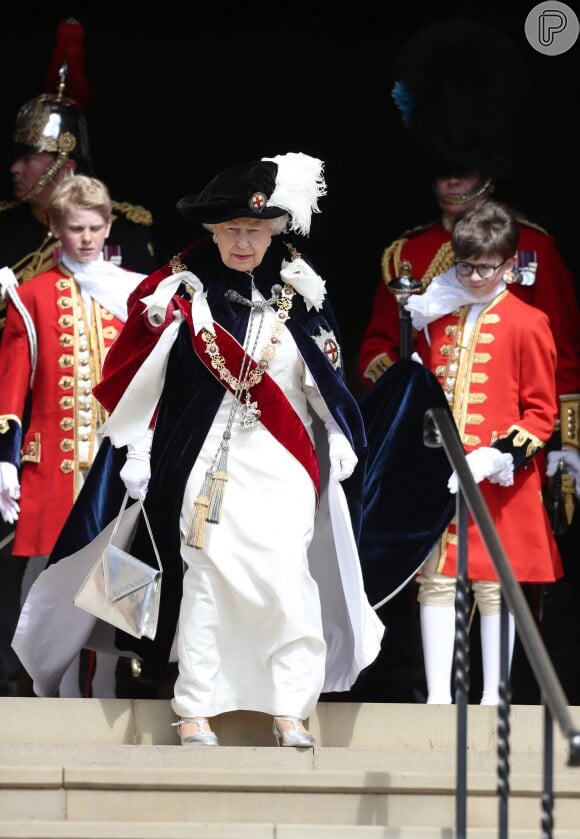 Rainha Elizabeth combinou o traje típico da monarquia com sapatos e bolsa metalizados na cor prata