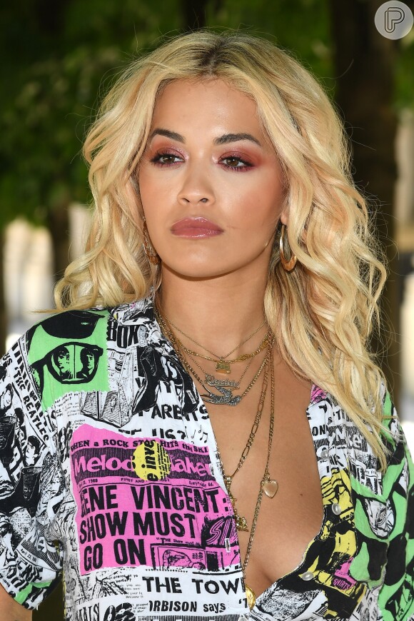 Na primeira fila do desfile de estreia de Virgil Abloh na Louis Vuitton, a cantora Rita Ora optou por camisa decotada. O show aconteceu na quinta-feira, 21 de junho de 2018, nos jardins do Palais Royal, em Paris