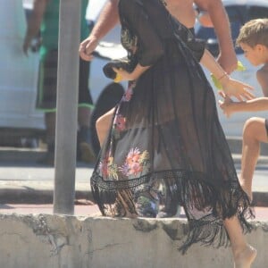 Fernanda Lima ajuda o filho gêmeo Francisco a subir a calçada da orla de Ipanema
