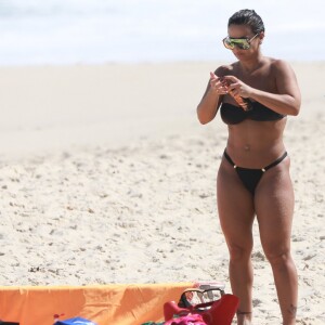 Viviane Araújo passa bronzeador em tarde na praia da Barra da Tijuca