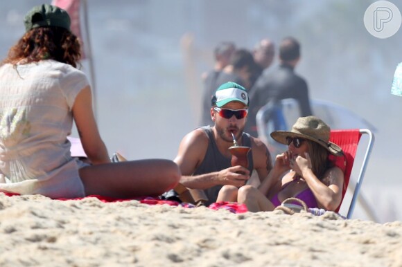 Rodrigo Hilbert toma chimarrão em tarde de praia com Fernanda Lima no Rio