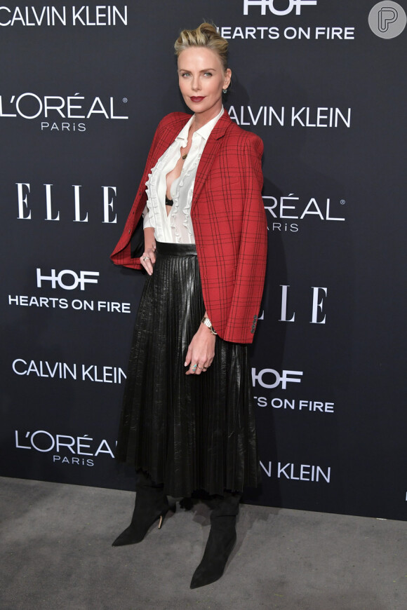 Poderosa, Charlize Theron escolheu um look clássico com saia plissada, camisa branca e blazer xadrez, tudo Dior