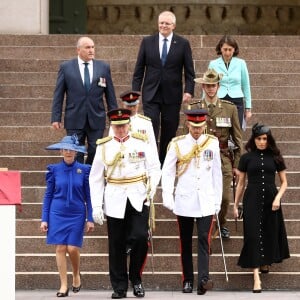 Meghan Markle e Príncipe Harry descem escadaria acompanhados de autoridades australianas