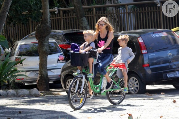 Fernanda Lima carrega os filhos na garupa da bicicleta