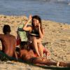Nathalia Dill conversa com amigos sentada em cadeira de praia