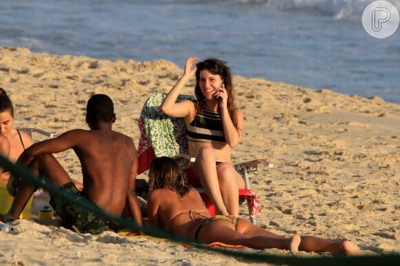 Nathalia Dill conversa com amigos sentada em cadeira de praia