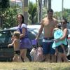 Thiago Lacerda e Vanessa Lóes levam babá para a praia, que carrega Cora, de 2 anos, no colo