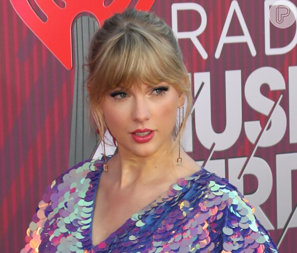 Taylor Swift arrasa no I Heart Radio com macaquinho metalizado e sandália com delalhe de borboleta