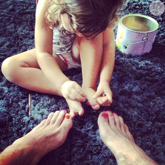 Olivia se diverte pintando as unhas do papai de vermelho e, vaidosa, aproveita para retocar as suas