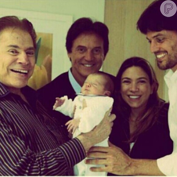 Silvio Santos segura, todo contente, seu neto Pedro. Ele é o primeiro herdeiro de Patricia Abravanel, filha do apresentador