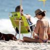 Juliana Paiva se diverte na praia com sua amiga e seu cachorro