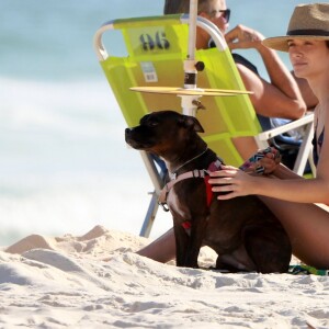 Juliana Paiva faz carinho em seu cachorro na praia