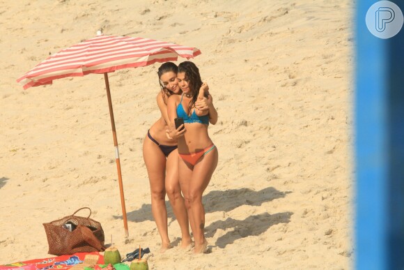 Débora Nascimento, de biquíni na praia, faz selfies com a atriz Maria Carol na praia do Arpoador entre uma gravação e outra da novela 'Verão 90'