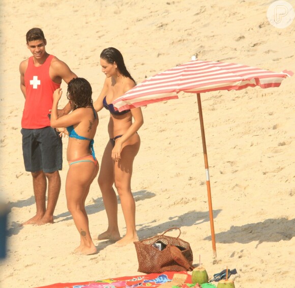 Débora Nascimento, de biquíni, grava na praia cenas da novela 'Verão 90' com a atriz Maria Carol