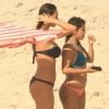 Na praia, Débora Nascimento exibe o corpo enxuto em cenas da novela 'Verão 90' com a colega de elenco Maria Carol