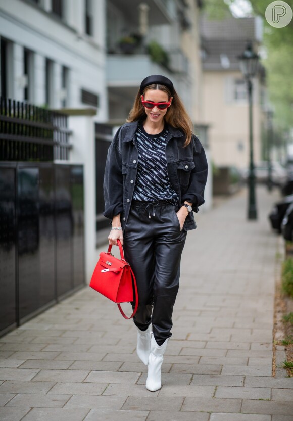 Calça de couro mais larguinha no estilo jogging, bota branca e bolsa vermelha. Vários contrastes em um look só