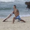 Paulinho Vilhena se estica na areia antes de surfar