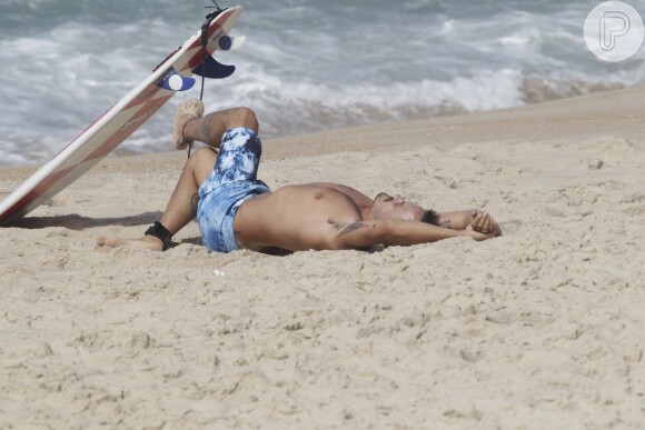 Paulinho Vilhena se alonga na areia antes de surfar