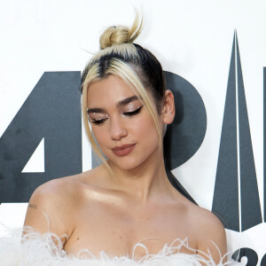 Um penteado chique e cool ao mesmo tempo é o coque alto e polido com mechas soltas na frente de Dua Lipa