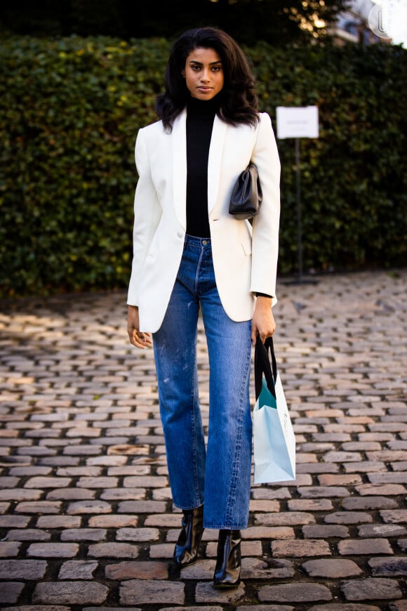 Calça jeans flare com blazer off-white sobre a blusa preta de gola alta