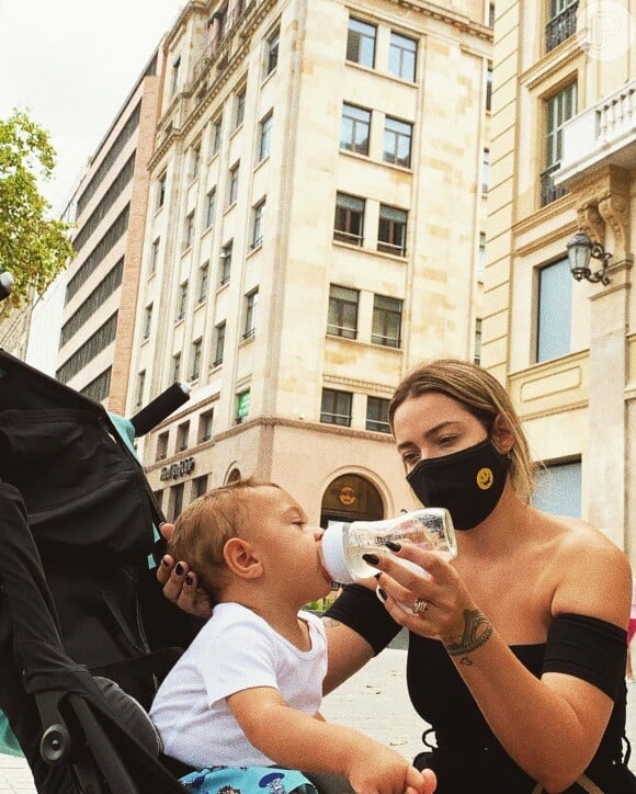 Carol Dantas posa dando água para o filho, Valentin, de 10 meses, em viagem na Espanha