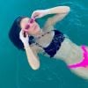 Flávia Pavanelli mergulha no mar com biquíni rosa neon