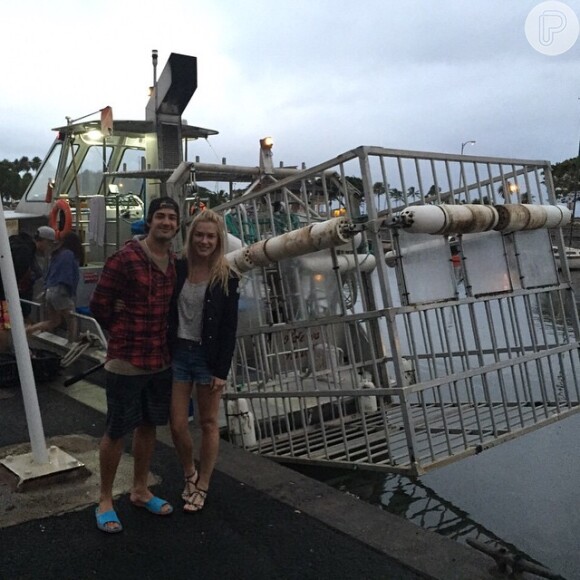 Fiorella Mattheis e Alexandre Pato posam ao lado de jaula para nado com tubarões