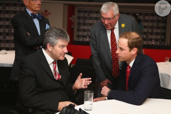 O príncipe William se diverte com a assinatura que deixou, aos 12 anos, no livro de ouro do estádio