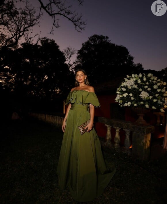 Vestido verde escuro com decote ombro a ombro foi escolhido por Marcella Tranchesi para casamento de noite