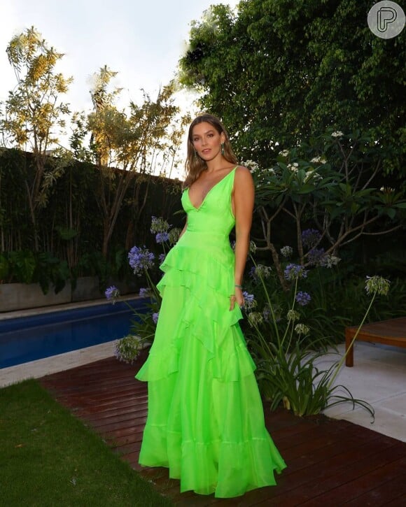 Vestido em tom neon de verde ficou elegante com modelagem repleta de babados escolhida por Ma Tranchesi