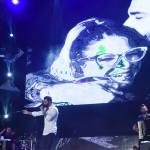 Gusttavo Lima projetou uma imagem em que aparece abraçando Marília Mendonça durante apresentação no Festival Caldas Country