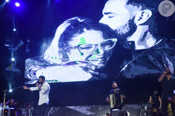 Gusttavo Lima projetou uma imagem em que aparece abraçando Marília Mendonça durante apresentação no Festival Caldas Country
